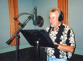 Picture of Michael Knott in the studio recording voice over narration. Mike is a narrator, announcer, voice actor with a deep baritone speaking and deep bass singing voice like Morgan Freeman, James Earl Jones, and a funny cartoon voice with his own recording studio.
